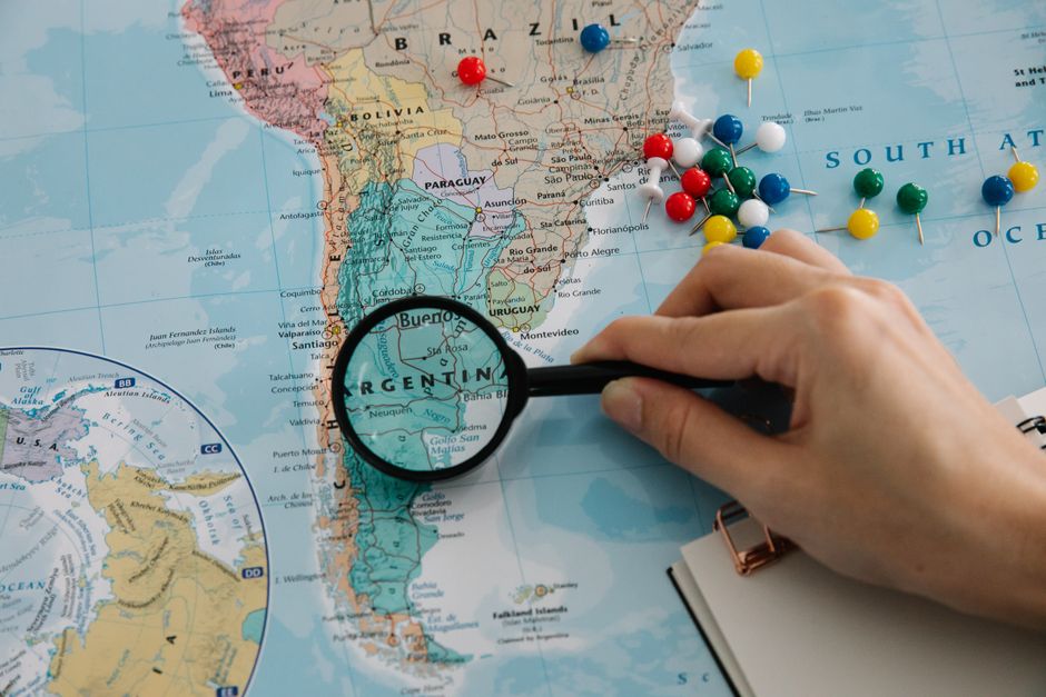Brightly lit, clean photo of a map with various locations marked by pins, all interconnected by a network of colored strin...