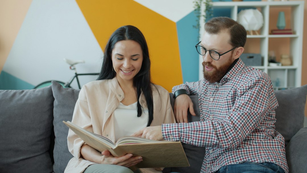 A modern, diverse couple sits at their sunlit kitchen table, smiling as they use a laptop to plan their finances together, symbolizing smart money moves.